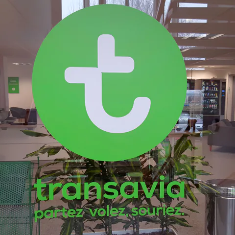 Logo Transavia sur une paroi vitrée de bureaux, réalisation Paristic