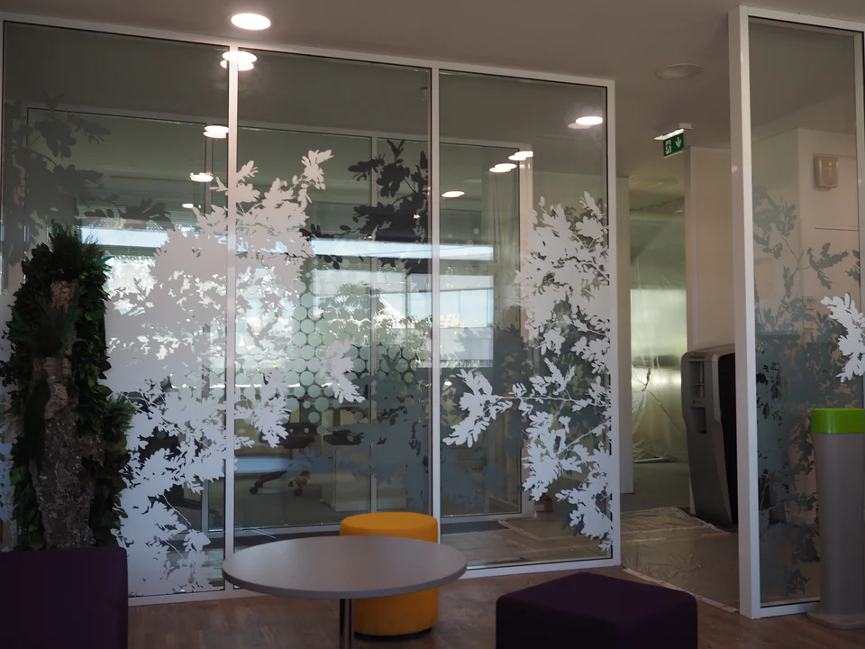Espace de pause des bureaux Veolia : parois vitrées habillées de feuillages blancs découpés, réalisation Paristic
