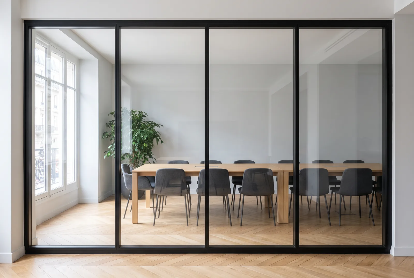 Salle de réunion derrière une cloison vitrée à quatre panneaux, vue de face